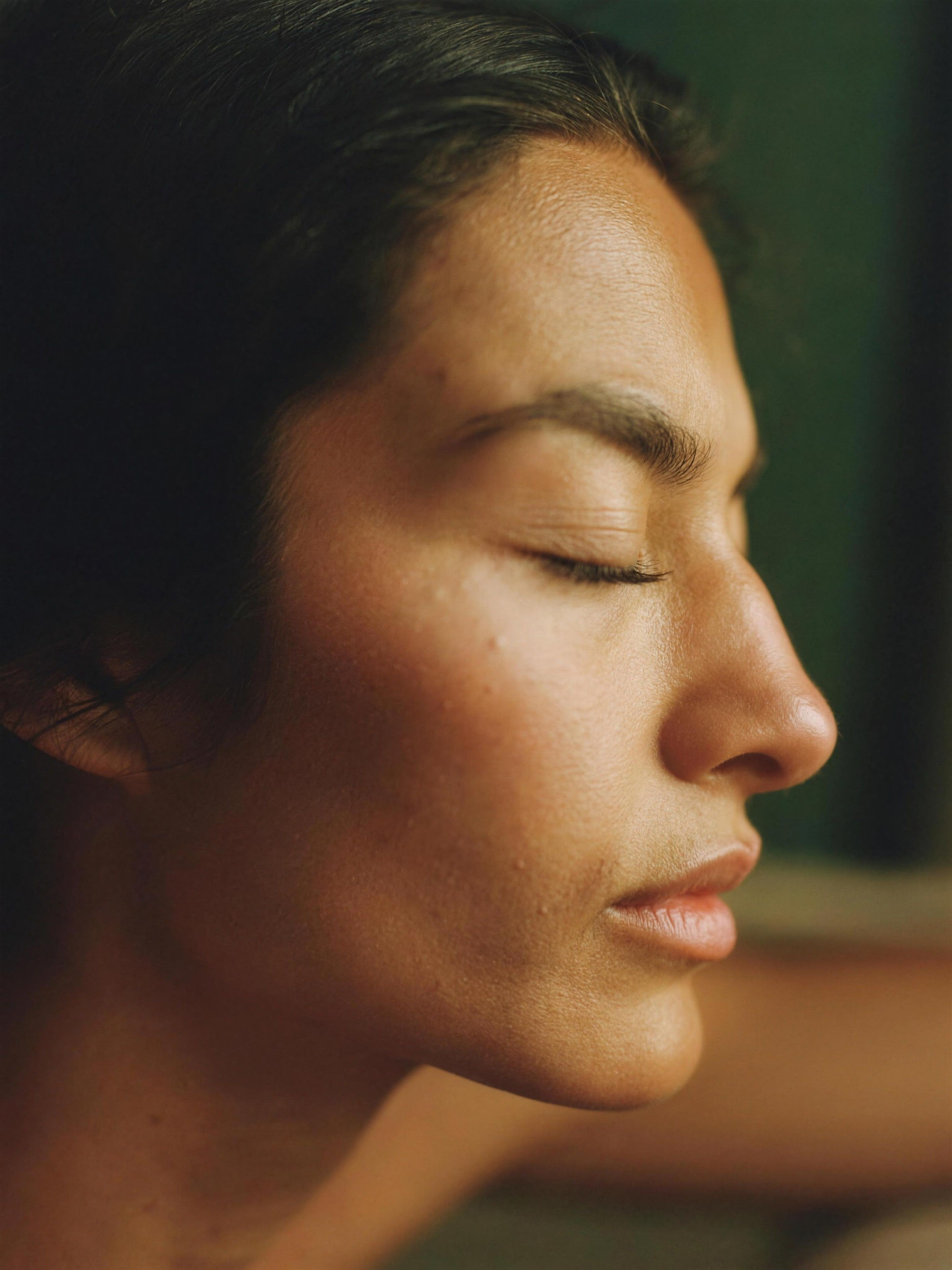 A woman resting with eyes closed in warm light